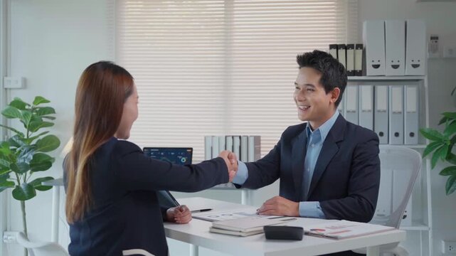 Colleagues sealing a deal, shaking hands across a desk after successful negotiations