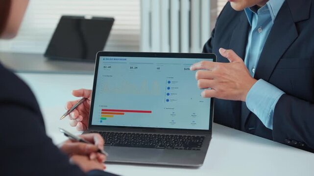 Business professionals analyzing financial data on a laptop screen and planning corporate strategy in an office meeting