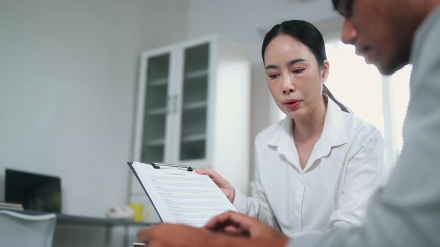 Asian businesswoman consulting a male client and showing a contract for signing a deal in an office meeting