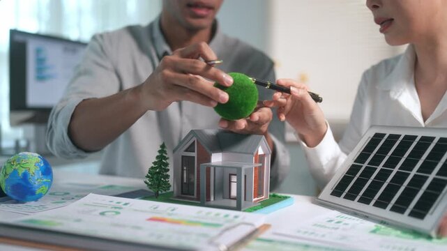 Architects discussing eco friendly house model with solar panel for sustainable green energy and a clean environment