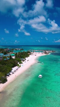 Aerial cloudscape over turquoise island, billowy white clouds above lush green shoreline, white sand beach and distant floating dome, expansive horizon and cinematic sky, Himmafushi island, Maldives