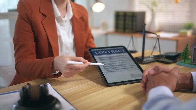 Lawyer explaining digital contract on tablet to client and asking for an electronic signature in office
