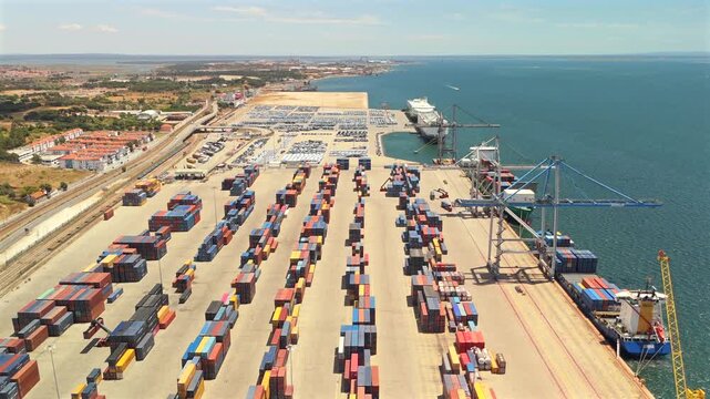 A drone view shows a large container terminal with stacked containers and gantry cranes