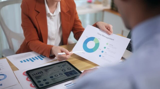 Business professionals analyzing data charts and graphs during a corporate strategy meeting with a tablet and documents