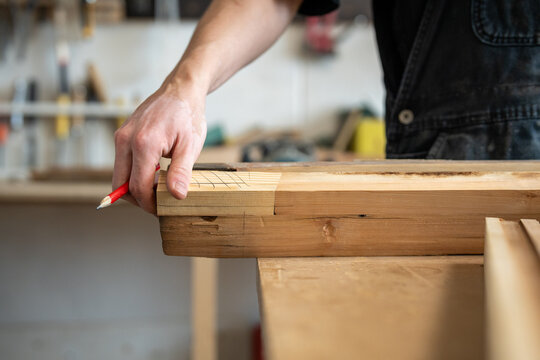 Craftsman hands holding and checking wooden patch details, selection of replacement for window frame, working process in restoration workshop, woodworker picking similar wooden planks for repair.