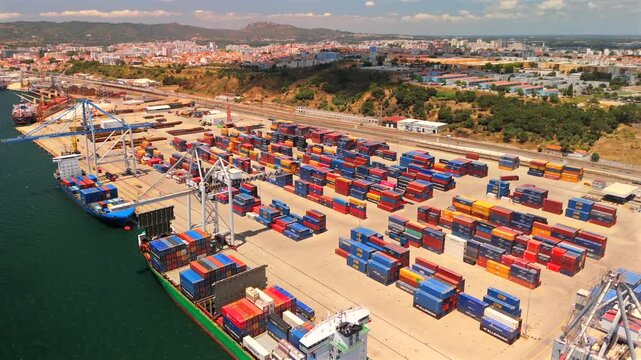 A drone orbits a busy terminal where a cargo ship rests alongside the quay