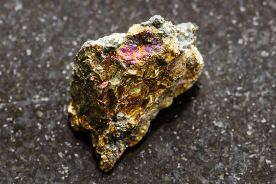 raw chalcopyrite rock close-up on black granite