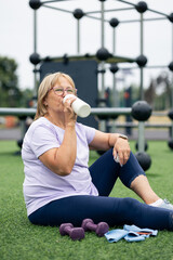 Obraz premium Senior woman drinking water resting after outdoor workout