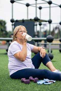 Senior woman drinking water resting after outdoor workout