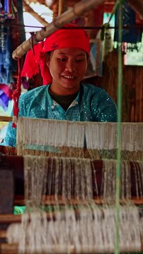 Smiling vietnamese woman weaving traditional fabric on loom