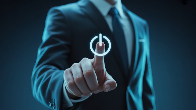 Professional businessman in a dark suit touching a glowing digital blue power button icon interface