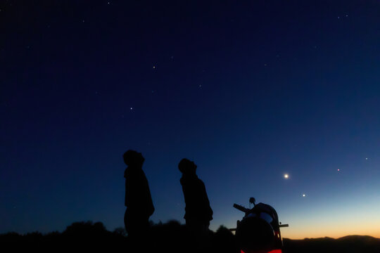 Amateur astronomers observing stars, planets, Moon and other celestial objects with a telescope in nature.