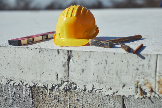 Construction tools and helmet on a cement foundation with iron rebar.