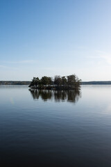 Obraz premium Lone Tree-Covered Island Adrift on a Vast High-Key Swedish Lake