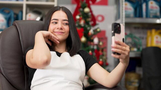 Young female employee taking selfies with a smartphone in a warehouse decorated for christmas
