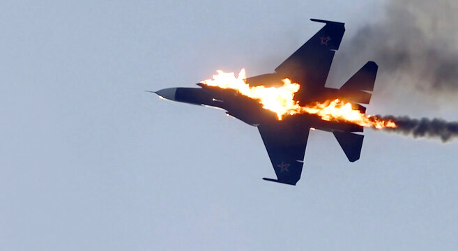 A military fighter jet engulfed in flames and trailing heavy smoke while in flight