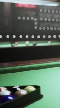 A pool table sits in a recreational space with a variety of colored balls arranged inside the rack. People gather around, ready to start a game and enjoy their time together.