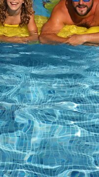 Happy family having fun on summer vacation. Father, mother and child playing in swimming pool. Active healthy lifestyle concept. Slow motion, vertical video