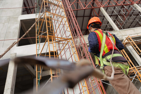 Construction worker in safety gear maneuvering on scaffolding at a building site focusing on engineering and safety practices