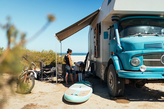 family unpacking surfboard next to vintage truck camper in deser