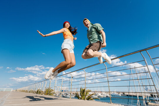 Cheerful young friends jumping outdoor enjoying summer