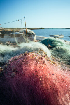 red fishing net in foreground with white fishing boats behind