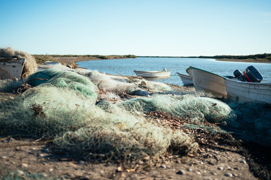 white fishing boats and colorful nets piled on sandy beach