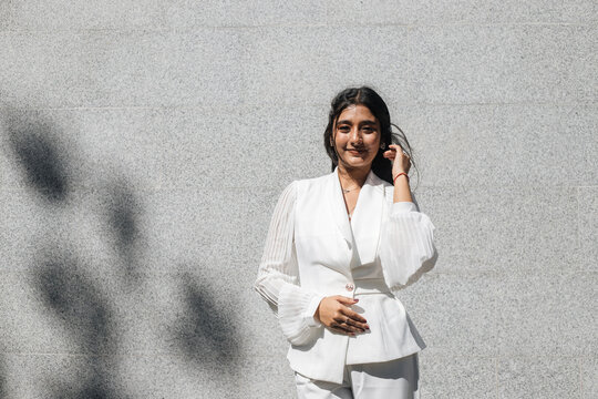 Smiling Indian woman against grey wall background.