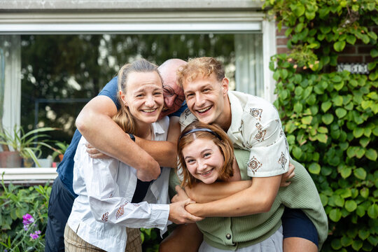 Family group hug and laughter in backyard garden