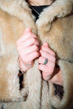Close up of hands clutching fur coat with direct flash