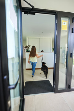 Woman entering veterinary clinic with dog on leash