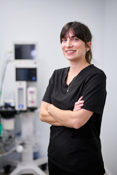 Female veterinarian smiling, standing in animal clinic