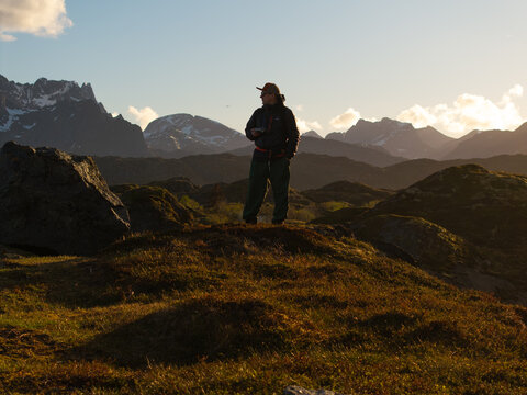 Lone hiker standing on a mountain ridge at sunset