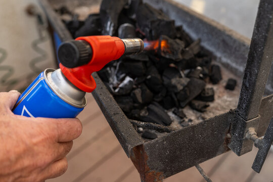Hand Using Torch on Charcoal for Grilling in Backyard