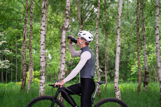 Cyclist Resting and Rehydrating in Nature