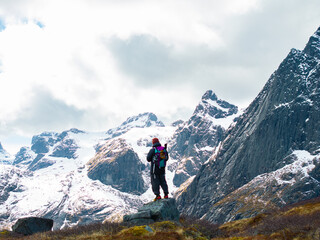Fototapeta premium Hiker Standing on a Rocky Ledge in a Snowy Mountain Landscape