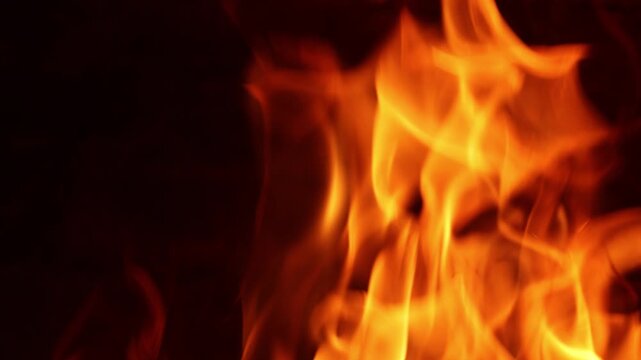 Cinematic slow motion horizontal close up of roaring intense orange fire flames. Pure texture against dark background, completely isolated without visible firewood. Perfect minimal background
