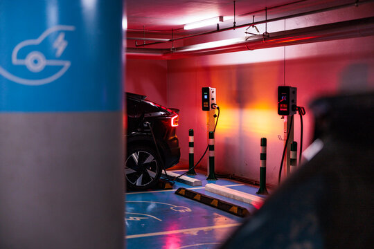 EV charging in a red-lit underground garage.