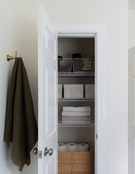 Organized Linen Closet with Folded Towels and Woven Storage Basket