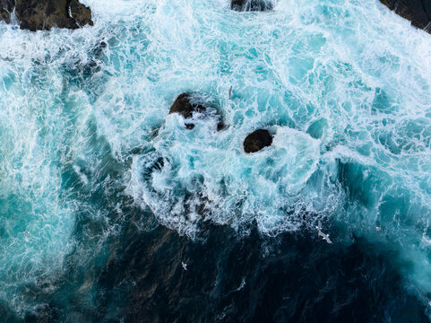 Powerful ocean waves crashing over dark coastal rocks