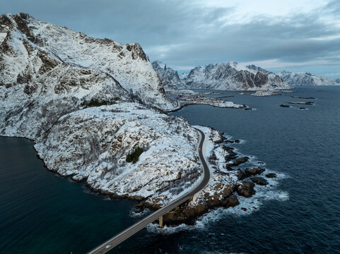 Snowy coastal road winding through rugged mountain seascape