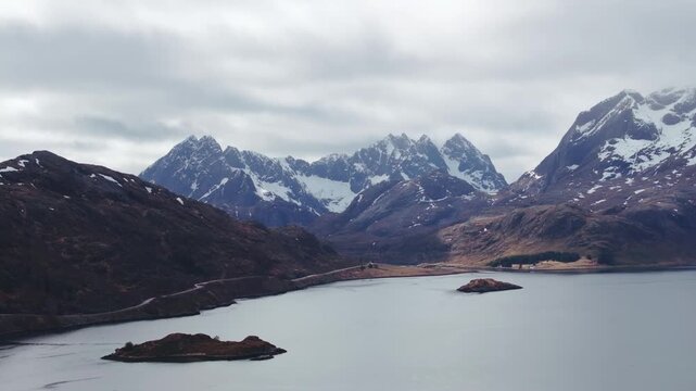 Aerial view of calm fjord with rocky islets and snow capped mountains