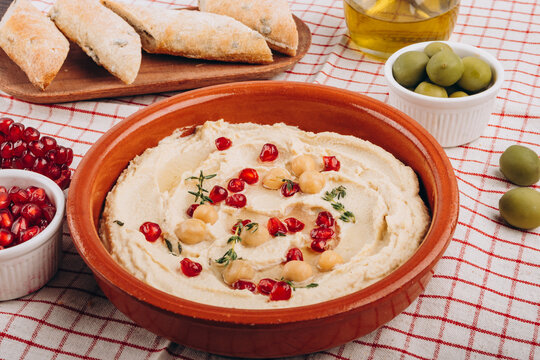 Creamy Hummus Bowl With Pomegranate Seeds, Chickpeas, Olive Oil and Rustic Bread
