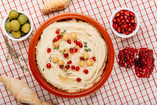 Creamy Hummus Bowl With Pomegranate Seeds, Chickpeas, Olive Oil and Rustic Bread