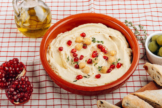 Creamy Hummus Bowl With Pomegranate Seeds, Chickpeas, Olive Oil and Rustic Bread