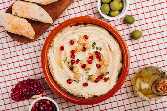Creamy Hummus Bowl With Pomegranate Seeds, Chickpeas, Olive Oil and Rustic Bread