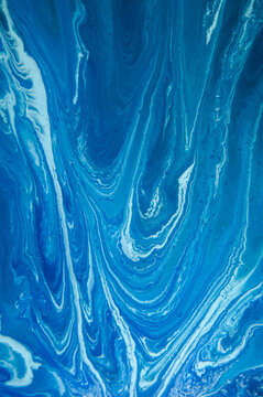 Swirling blue patterns in a fluid art piece created with paint and resin