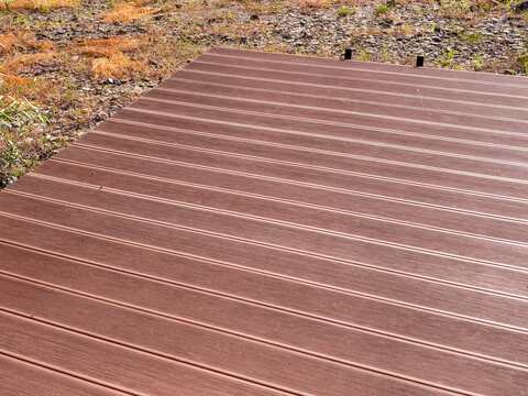 Brown WPC composite decking platform with grooved anti-slip surface. Modern outdoor deck made from composite boards, suitable for terraces, docks and garden structures.