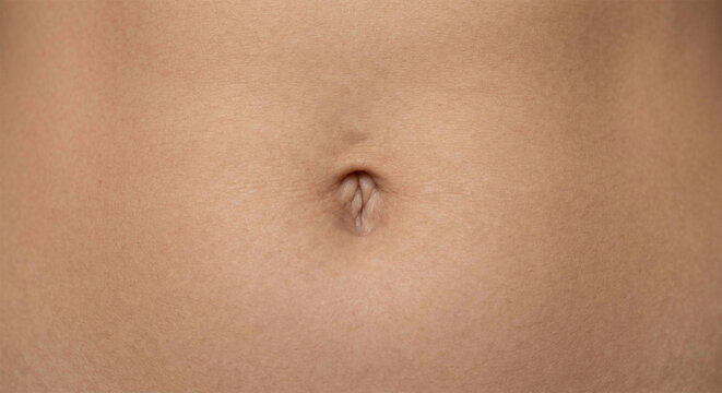 Extreme close-up of a human navel on natural skin texture background