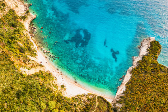 Aerial top down view secluded non commercialized Filikuri rocky beach.Clear turquoise Ionian sea meets steep rocky coastal cliffs. Scenic Albanian Riviera travel landscape in Himar, Albania.